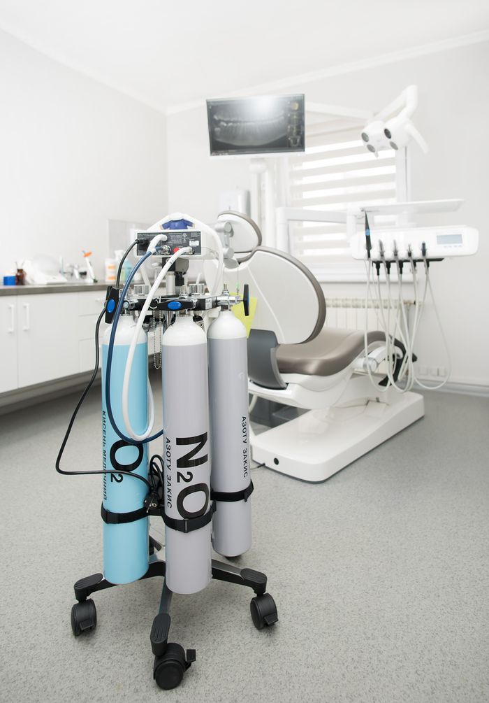 Bright dental clinic room featuring cutting-edge equipment and medical gas tanks for professional use.